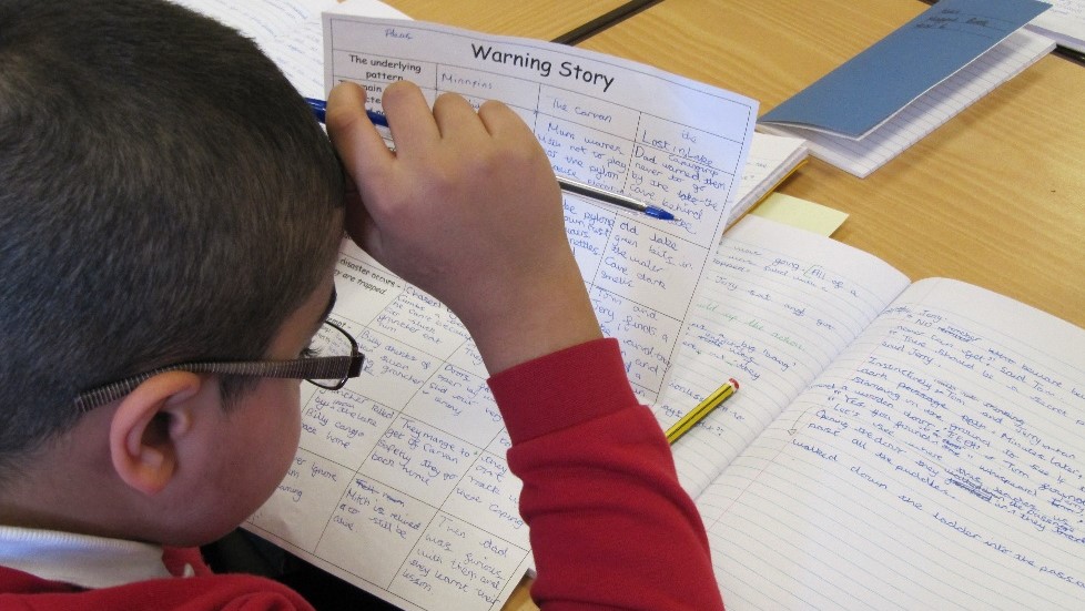 Pupil concentrating on writing Yew Tree Community School