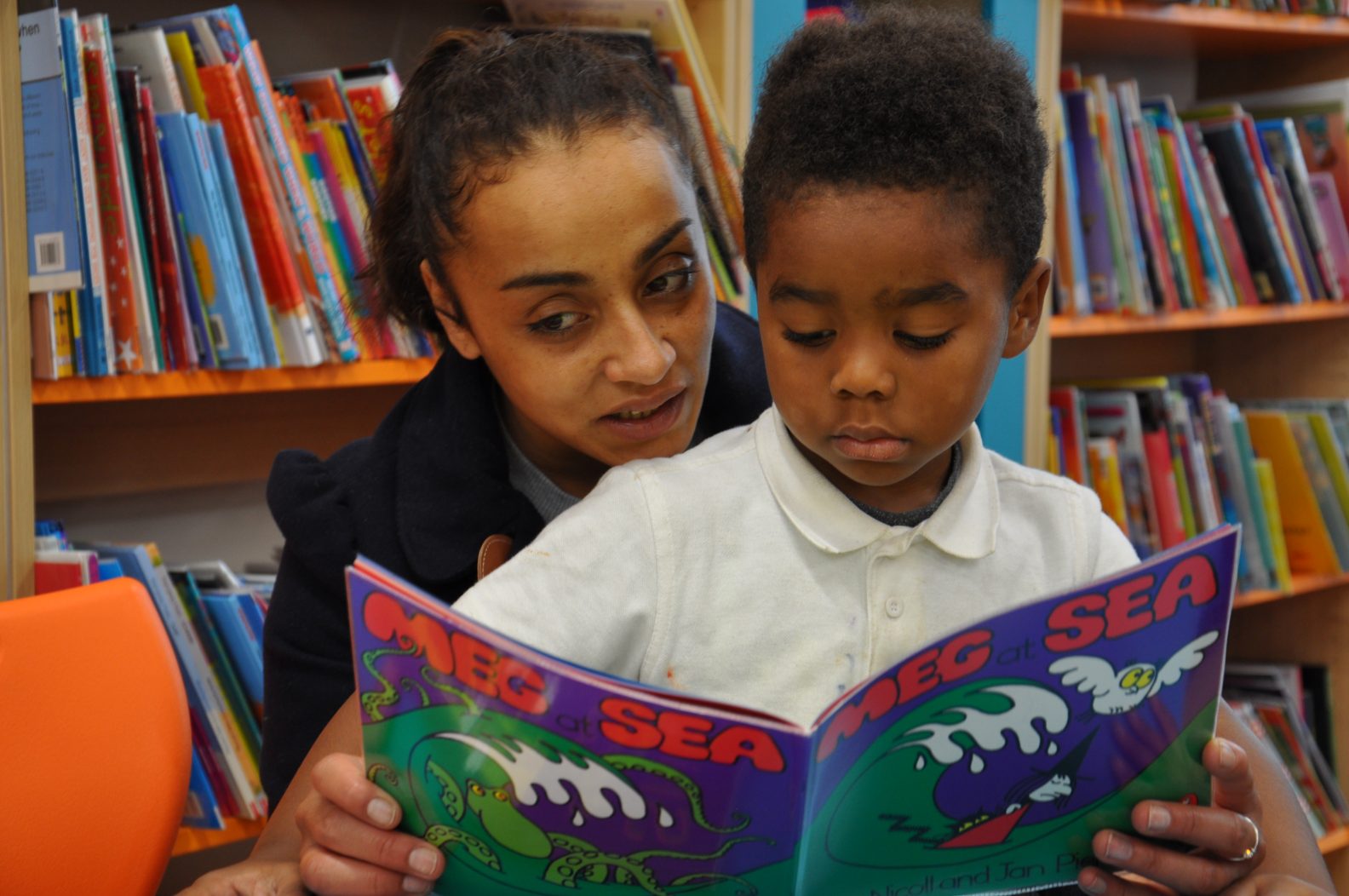 Teacher and pupil sharing reading book